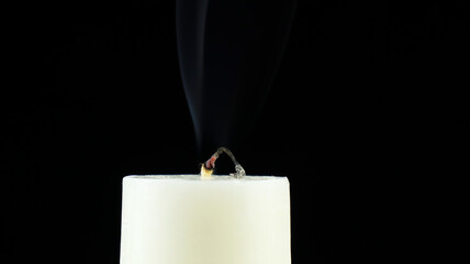 A candle whose fire goes out and leaves ashes on a black background