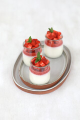 Italian dessert panna cotta with fruit jelly and fresh pieces of strawberries on white background. Copy space