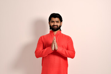 handsome indian man wearing kurta smiling making Namaste gesture with hands, looking at camera
