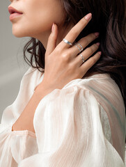 Beautiful young girl posing hand wearing rings and jewellery touching her hair and neck.