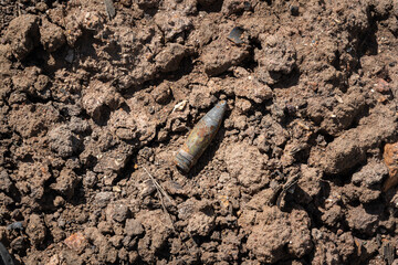 A rusty old sniper rifle or heavy machine gun bullet caliber which is remined on the desert ground of the war battlefield.