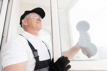 Naklejka na ściany i meble Joinery worker man installs plastic upvc white windows with vacuum lifter