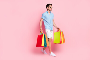 Profile photo of man walk carry shop bargains empty space wear sunglass blue shirt isolated on pink...