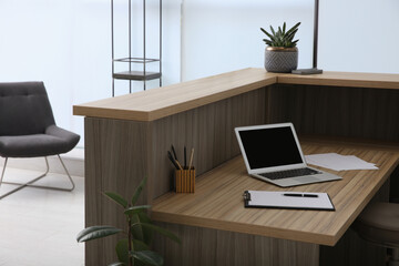 Stylish modern wooden desk with laptop indoors. Receptionist workplace