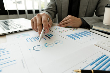 Businessman pointing at graph and chart to analysis use for plans to improve quality, business finances and accounting concept