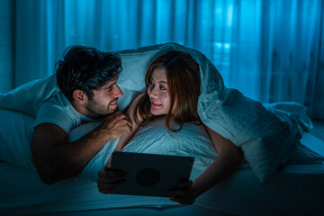 A couple is happy to look at something on the computer together in the bedroom.