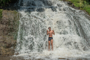 Fototapeta na wymiar The joy of a boy bathing in a waterfall.