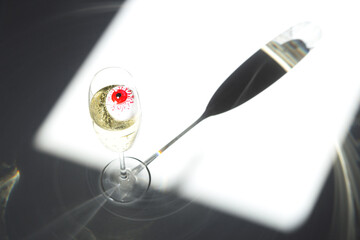 Red eye in a champagne glass in sunlight. Elegant Halloween decor. Autumn holiday concept. Top view, flat lay