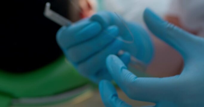 A close-up metal archwire is laying on the table and a medical worker is taking the wire than by using orthodontic wire cutters straight is bite off a piece of wire.