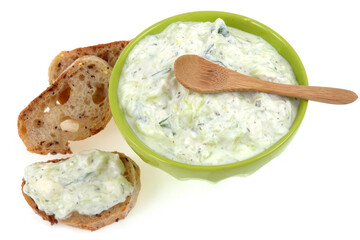 Bol de tzatziki avec une cuillère en bois et des tartines de pain en gros plan sur fond blanc