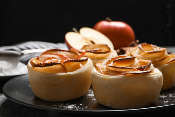 Freshly baked apple roses on black background, closeup. Beautiful dessert