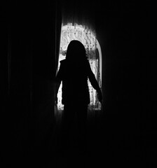 Silhouette of an unknown shadow figure on a door through a closed glass door. The silhouette of a human in front of a window at night.