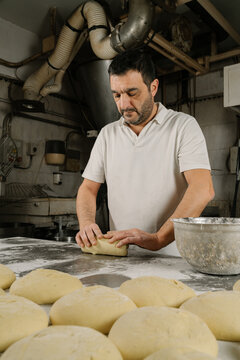 Ethnic baker preparing bread at table in kitchen