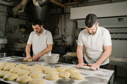 Ethnic bakers preparing bread at table in kitchen