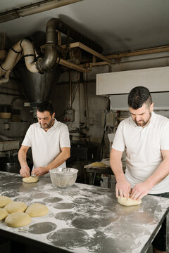 Ethnic bakers preparing bread at table in kitchen