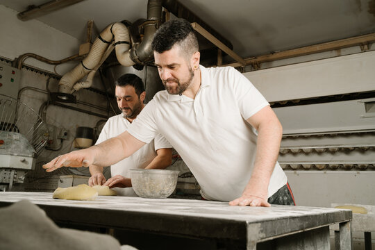 Ethnic bakers preparing bread at table in kitchen