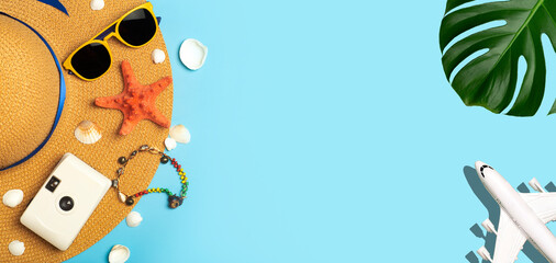 Travel summer background. Sunglasses, hat, palm tropical leaves, seashells, airplane and beach accessories on a colored blue background. Tourist vacation, relaxation and summer concept.