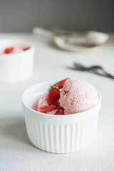 Delicious Strawberry Ice Cream with fresh strawberries in a bowl on light concrete background. Selective focus