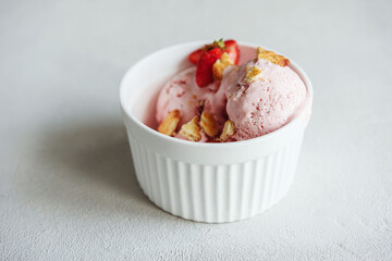 Delicious Strawberry Ice Cream with fresh strawberries and cookies in a bowl on light concrete background. Selective focus