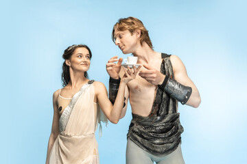 Coffee time. Young couple of ballet dancers in ancient Rome costums at blue studio.