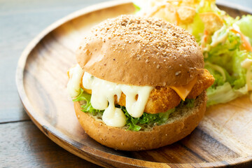 Fried fish fillet burger with vegetable salad on wood plate background