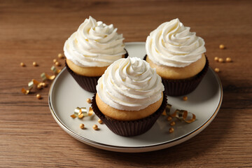 Delicious cupcakes decorated with cream on wooden table
