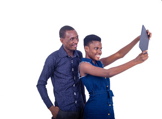 young man and woman taking photos together using a digital tablet while smiling.