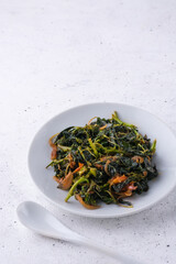 amaranthus or amaranth dish, healthy green leafy vegetarian curry dish with a spoon on a white textured surface