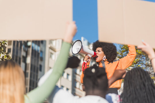 Black protester speaking into loudspeaker against unrecognizable multiethnic people outdoors