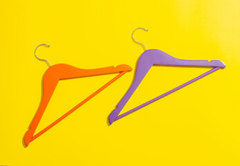 Orange and purple wooden hanger on yellow background in close-up.