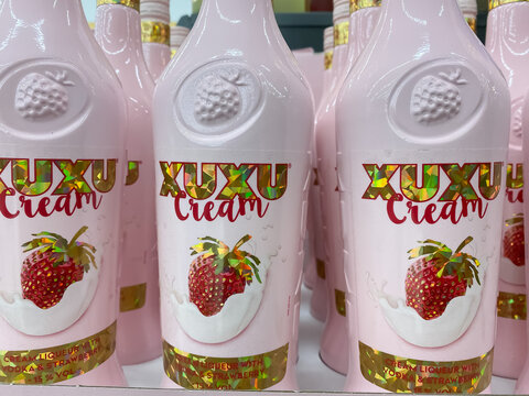 Viersen, Germany - June 9. 2021: Closeup of pink bottles with xuxu cream strawberry liqueur in shelf of german supermarket