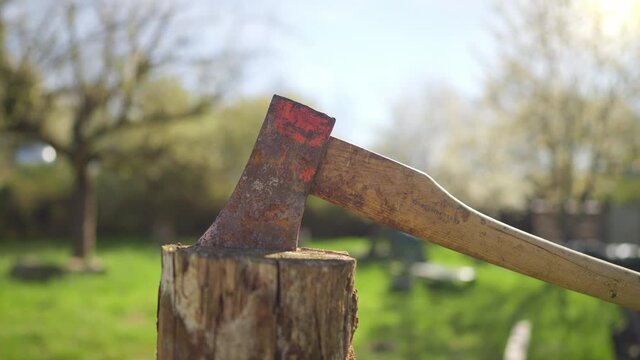 Man in plaid shirt and straw hat is chopping wood in garden at sunny spring day shot in 4k super slow motion