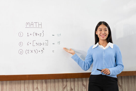 Educational concept a young smart female teacher explaining decision of hard math in a classroom before Covid-19 epidemic