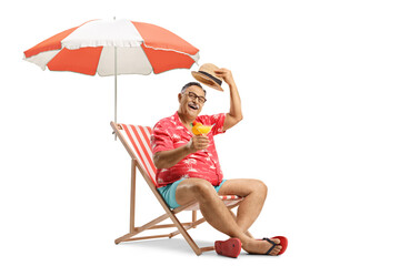 Mature tourist toasting with a cocktail and sitting on a beach chair under an umbrella