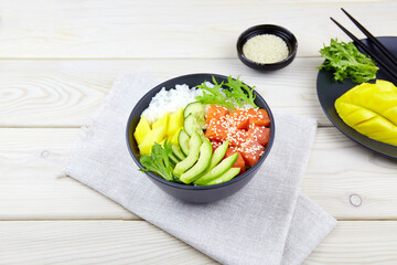  Poke bowl of salmon, avocado, rice, cucumber, mango, herbs . Hawaiian ahi, a diet meal with fish. Top view. Close-up