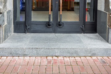 a threshold with a step at the threshold entrance to the store with a black iron door with glass...