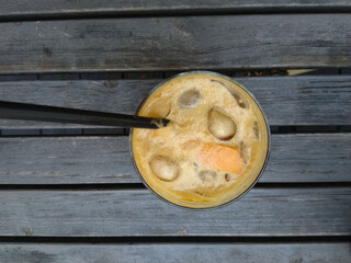 Front top photo of a glass of coffee cocktail with tonic, ice and orange on a wooden table 