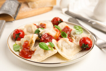 Tasty ravioli with tomato sauce served on white table