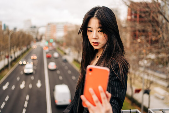 Long hair brunette Asian woman using mobile phone in the street