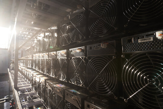 Bitcoin ASIC miners in warehouse. ASIC mining equipment on stand racks for mining cryptocurrency in steel container. Blockchain techology application specific integrated circuit units storage.