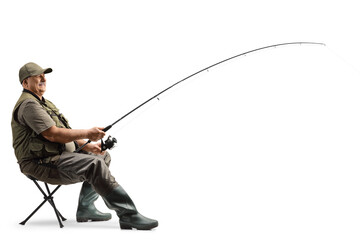 Profile shot of a mature fisherman sitting on a chair with a fishing rod