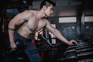 Fototapeta na wymiar Handsome man working out in the gym, Asian man doing weightlifting to compete in sports,Pull up dumbbell for back training muscle