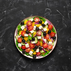 Greek salad in a plate on a black stucco background. Top view, flat lay. Square photo.