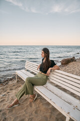 Attractive brunette sits on the sand beach. Concept of serenity at the beautiful place near the sea
