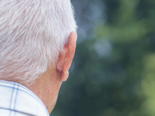 Back view of head an elderly man with short gray hair while standing outdoors. Close-up. Space for...