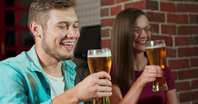 Group of friends enjoying a beer at pub in Poland, toasting and laughing - Multiracial group of people having fun together and drinking a pint of beer - Lifestyle and drinks