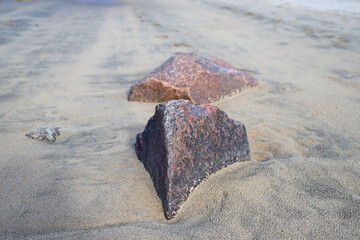 textured fragments of natural granite on a sandy beach