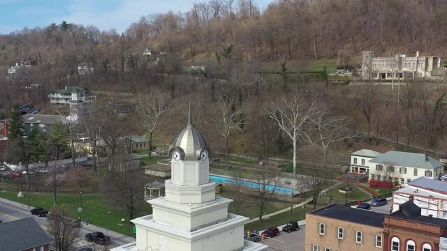 Aerial camera moving left past Berkeley Springs courthouse showing park and castle in winter and the cusp of spring.