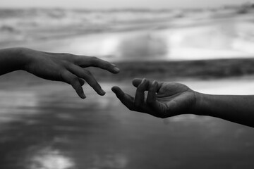 Helping hands abstract art in black and white background. Hands of two people reaching out each...