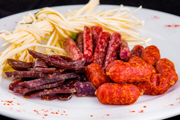 Beer appetizer: cecil cheese, picolini sausages, sujuk, jorki. Plate with delicious sliced smoked sausages